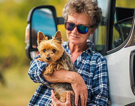 Woman holding pet dog next to motorhome